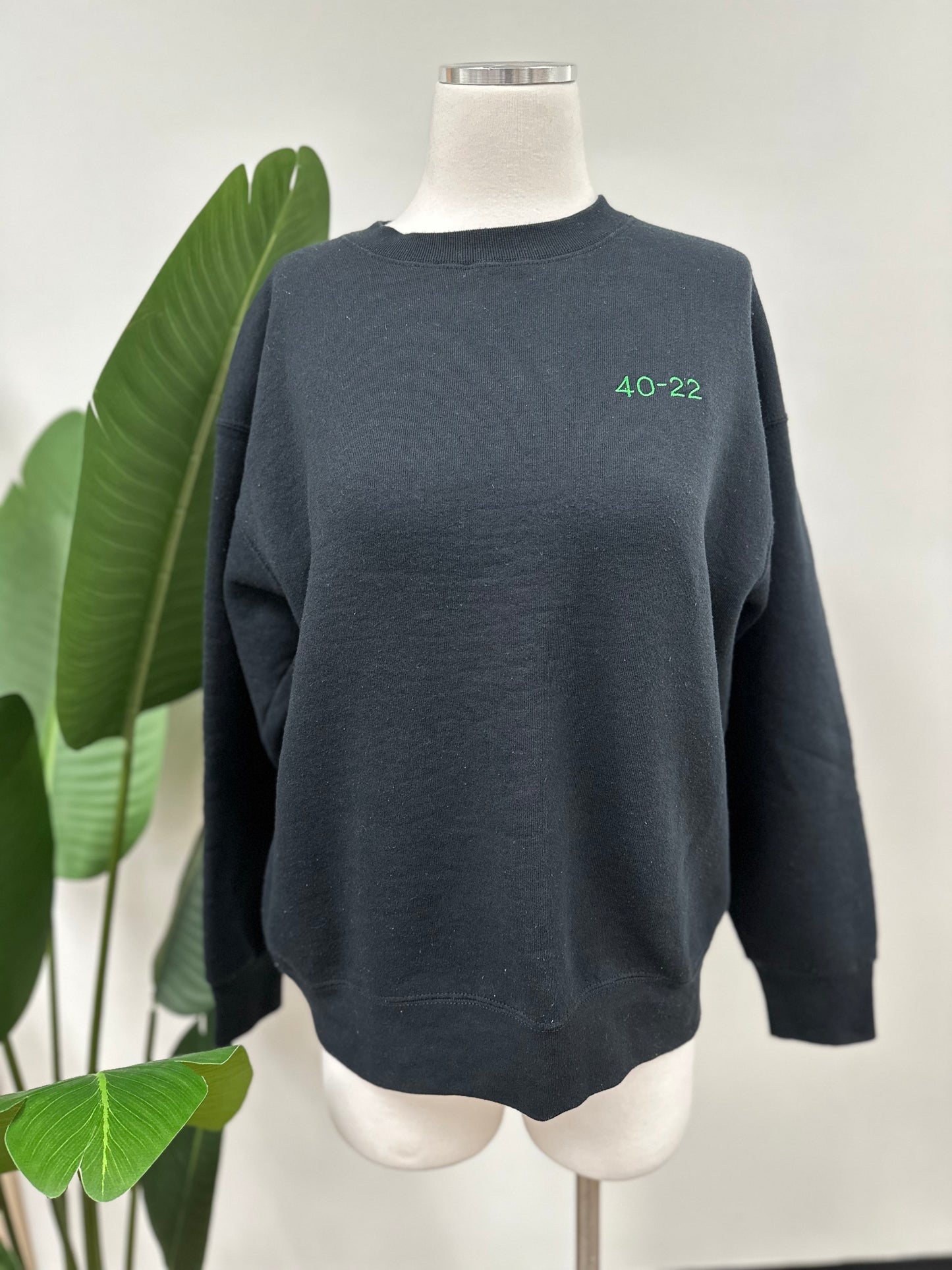 Front view of a vintage black crewneck with green embroidered Super Bowl score