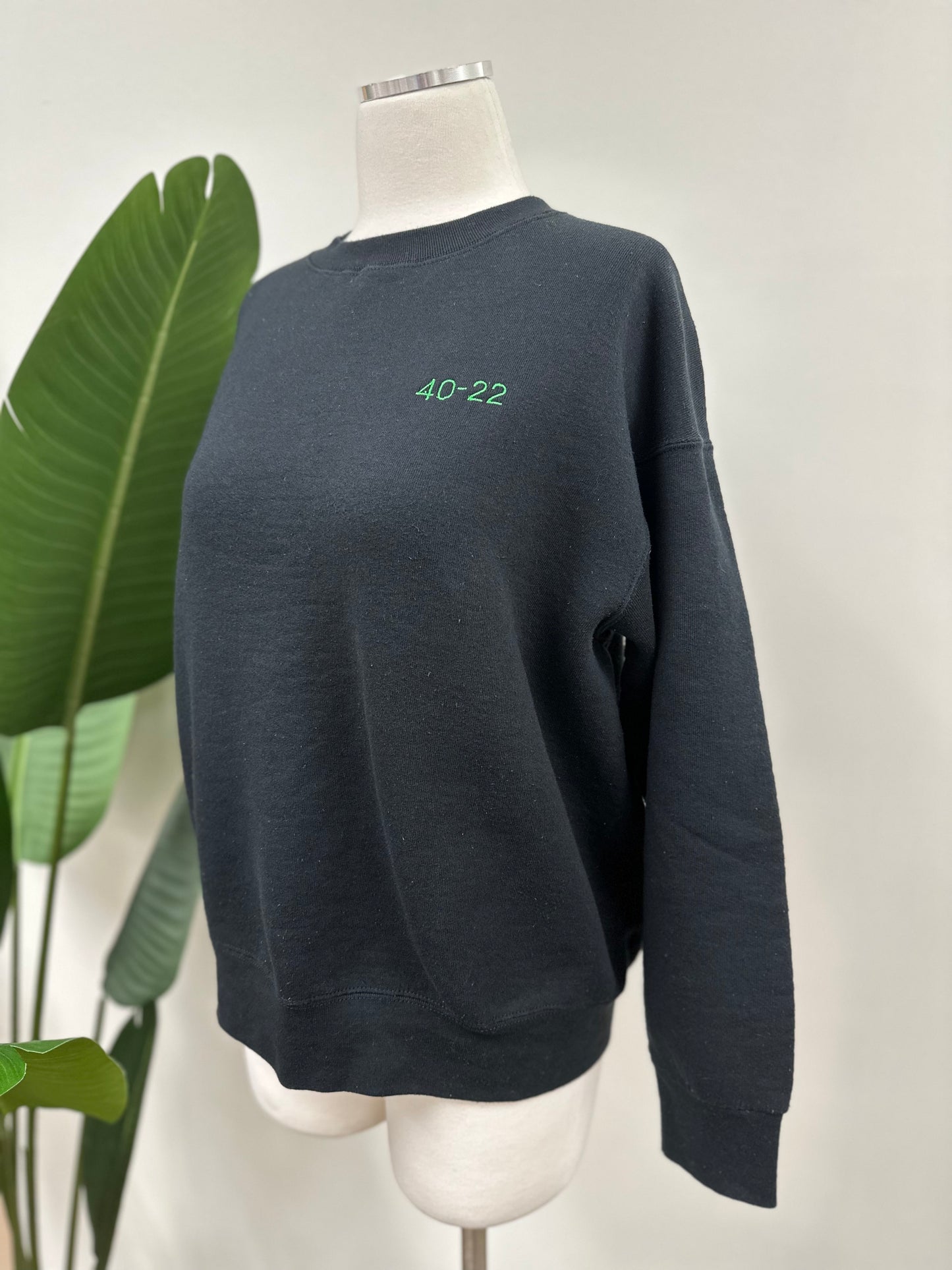 Side view of a vintage black crewneck with green embroidered Super Bowl score