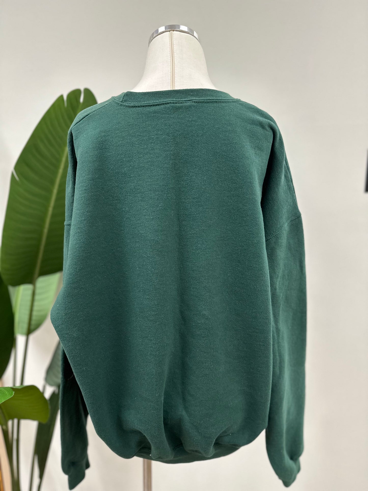 Back view of a green vintage crewneck with a white embroidered Super Bowl Score