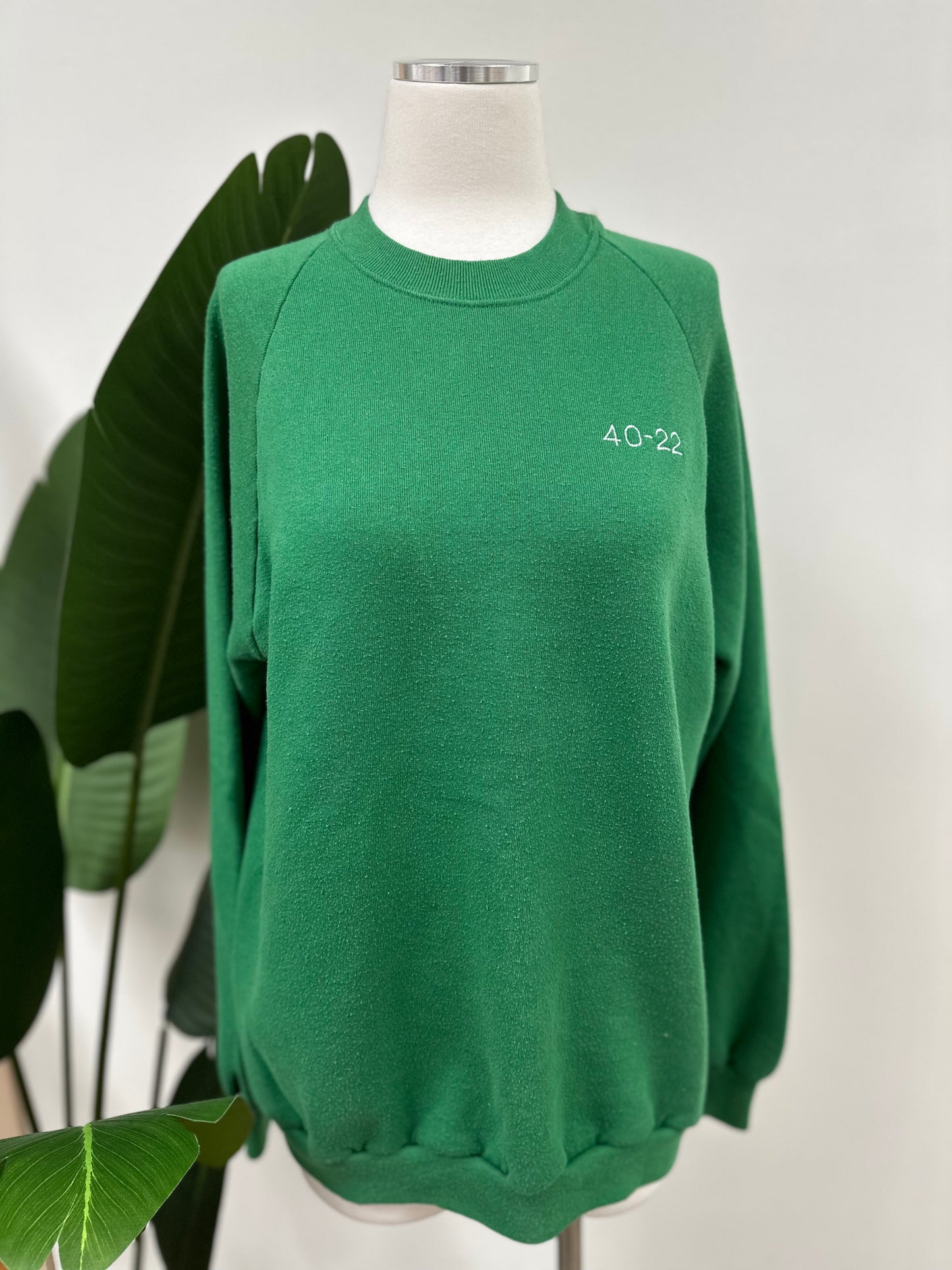Front view of a kelly green vintage crewneck with a white embroidered Super Bowl Score