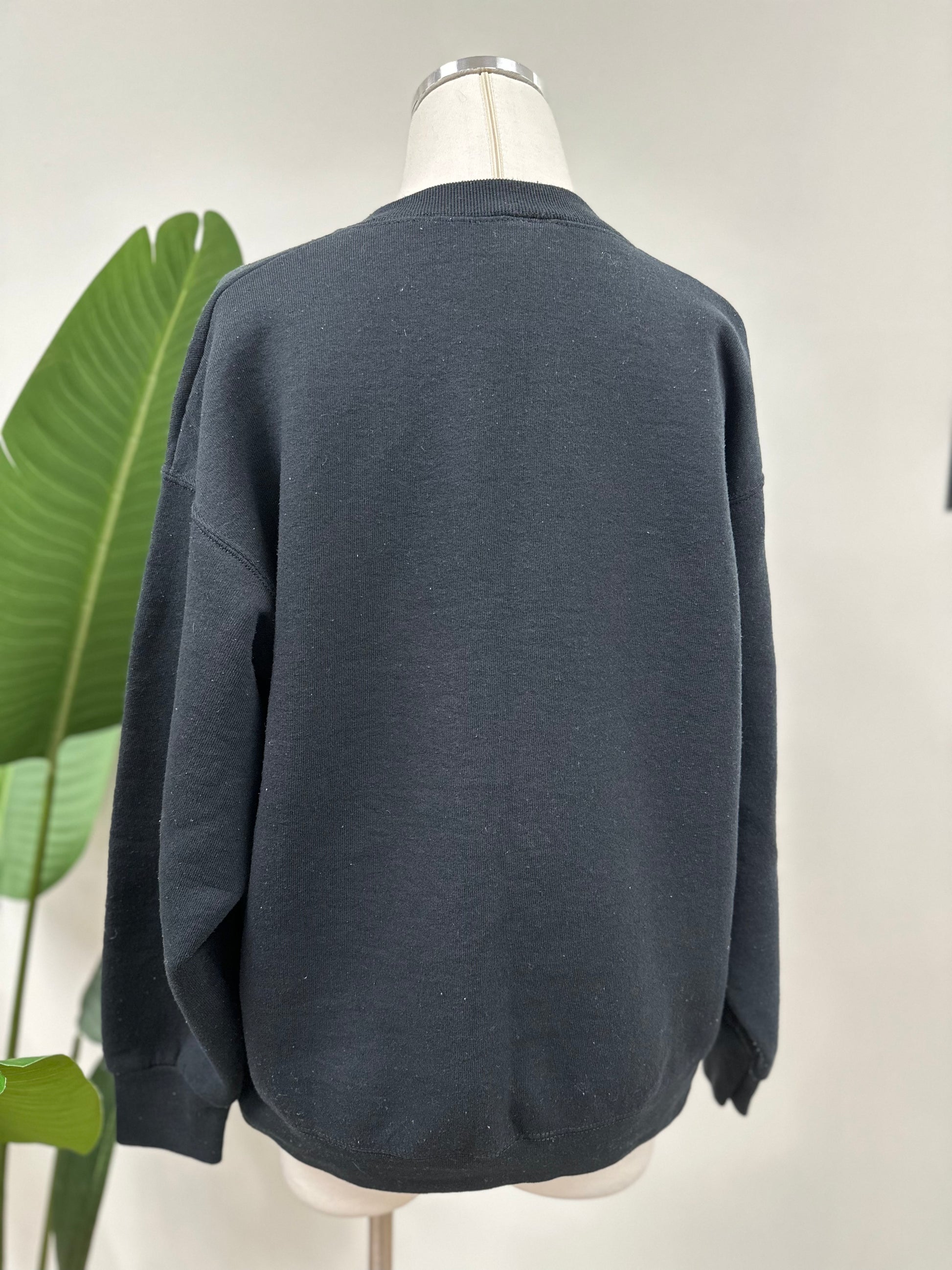Back view of a vintage black crewneck with green embroidered Super Bowl score 