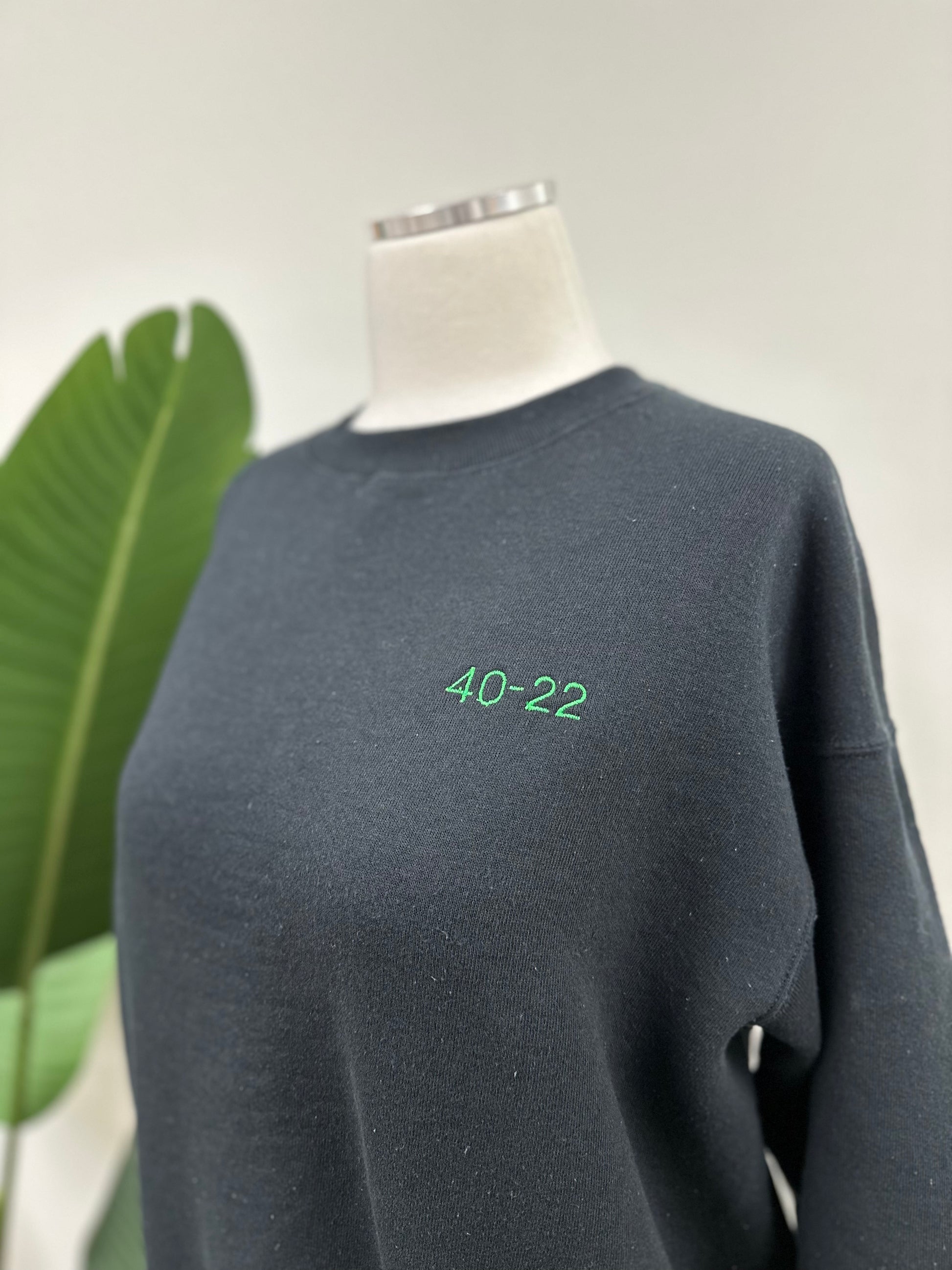 Close up view of a vintage black crewneck with green embroidered Super Bowl score