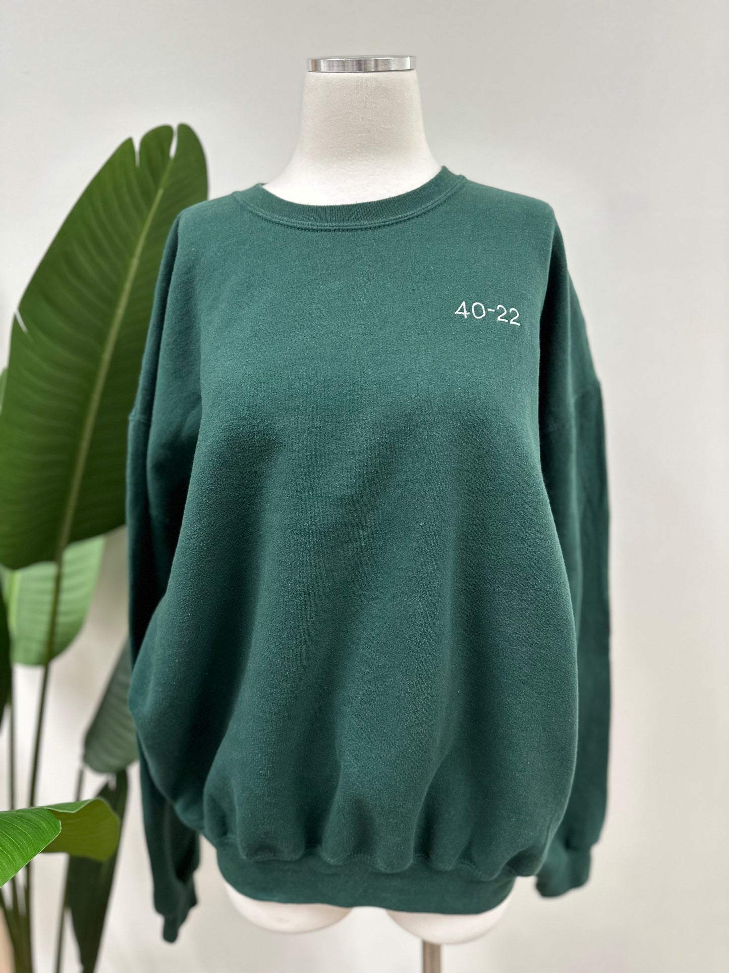 Front view of a green vintage crewneck with a white embroidered Super Bowl Score