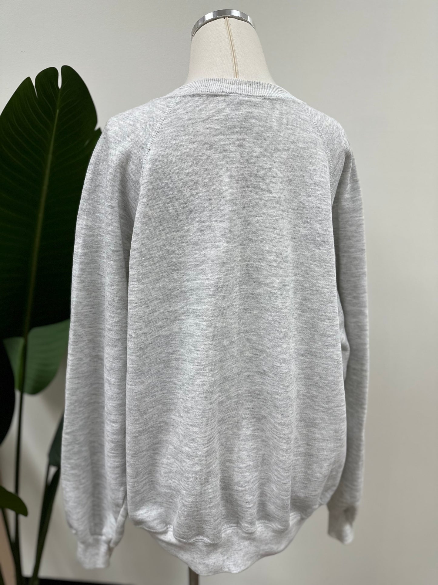 Back view of a heather grey vintage crewneck with a green embroidered Super Bowl Score